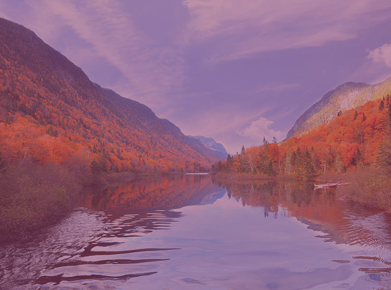 Photographie d'un lac calme entouré de collines et d'arbres au Québec